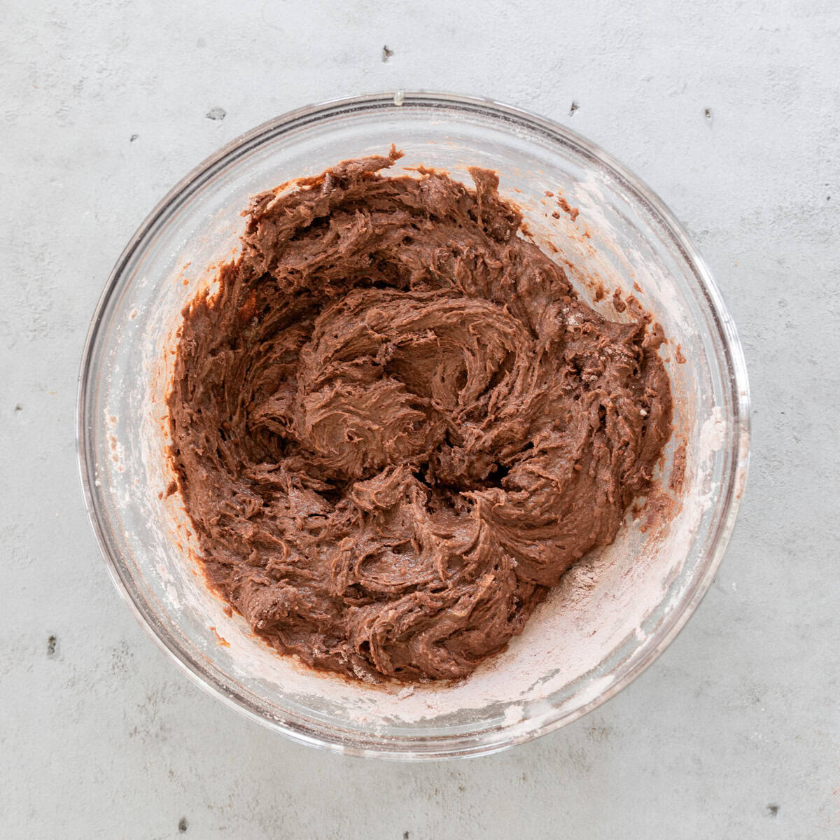 the wet and dry ingredients combined in a glass bowl on a grey background.