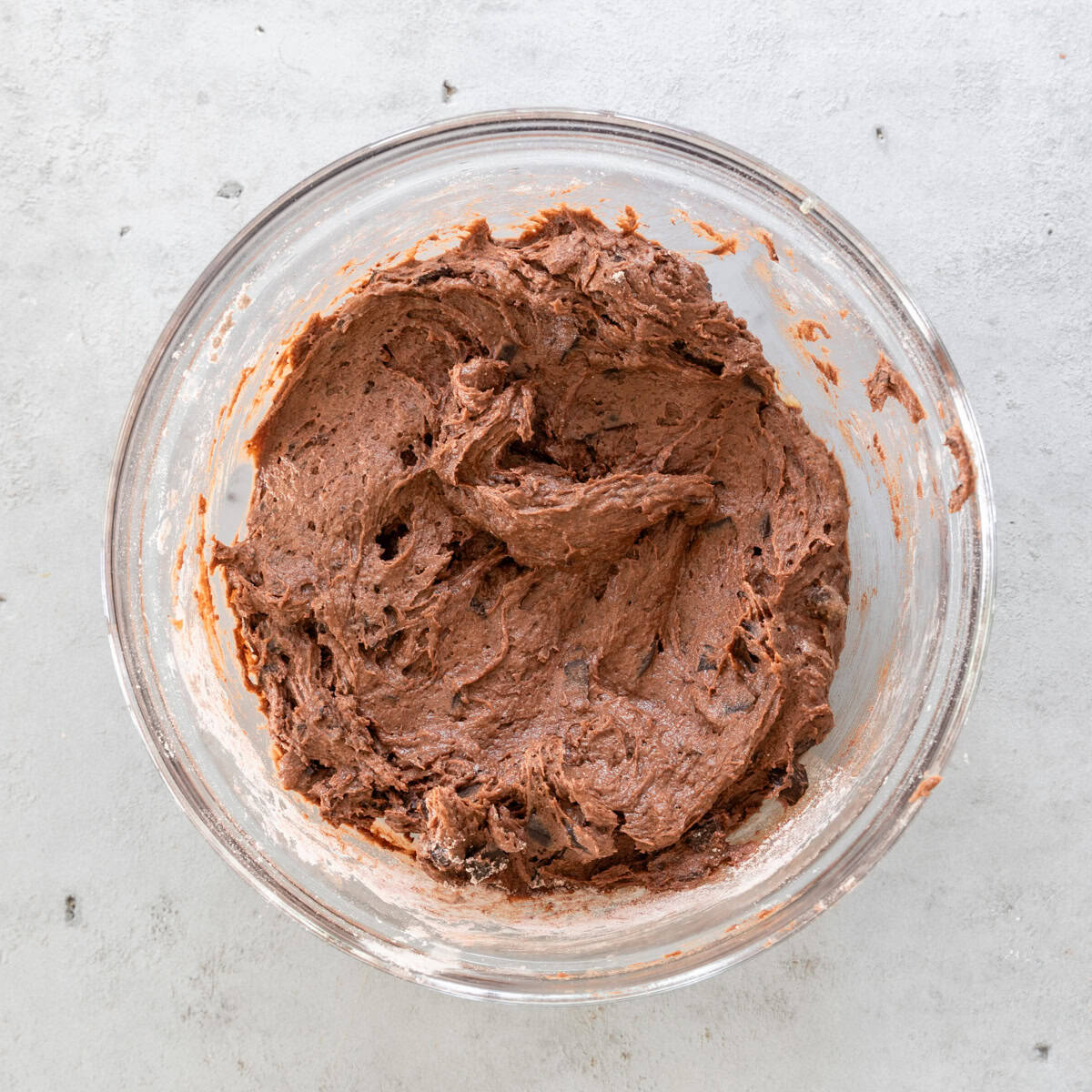 the completed chocolate banana cookie dough in a glass bowl on a grey background.