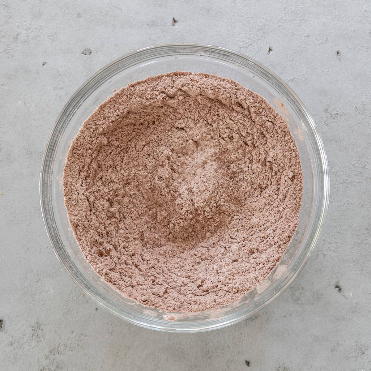the dry ingredients combined in a glass bowl on a grey background.