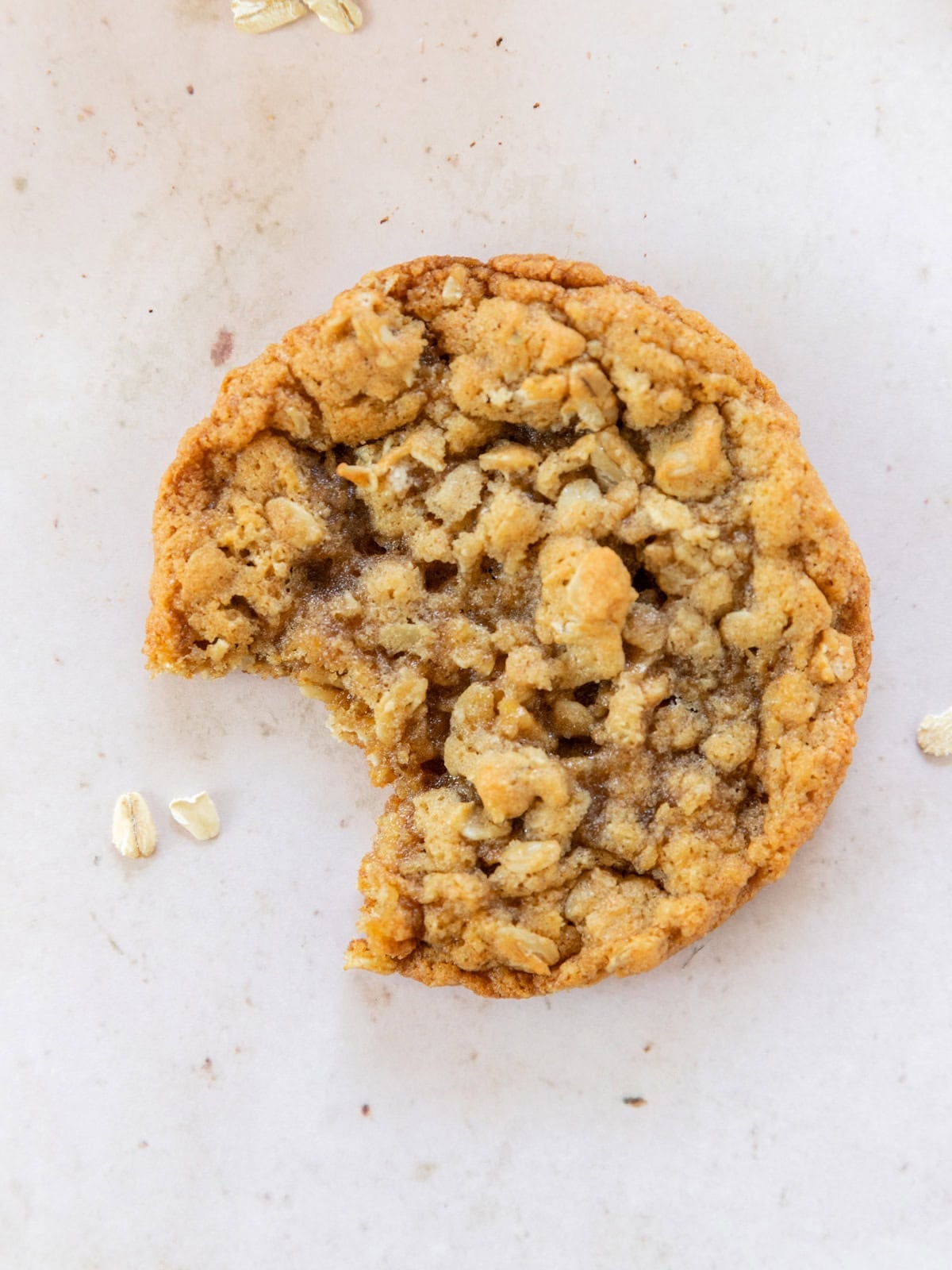 an oatmeal cookie with a bite out of it on a tan background.