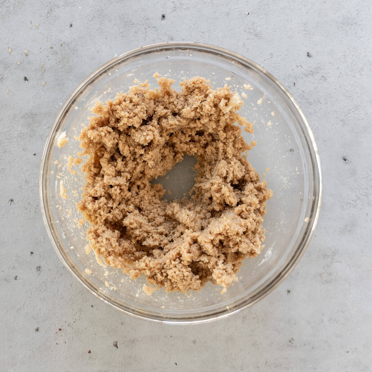 the butter and brown sugar combined in a glass bowl on a grey background.
