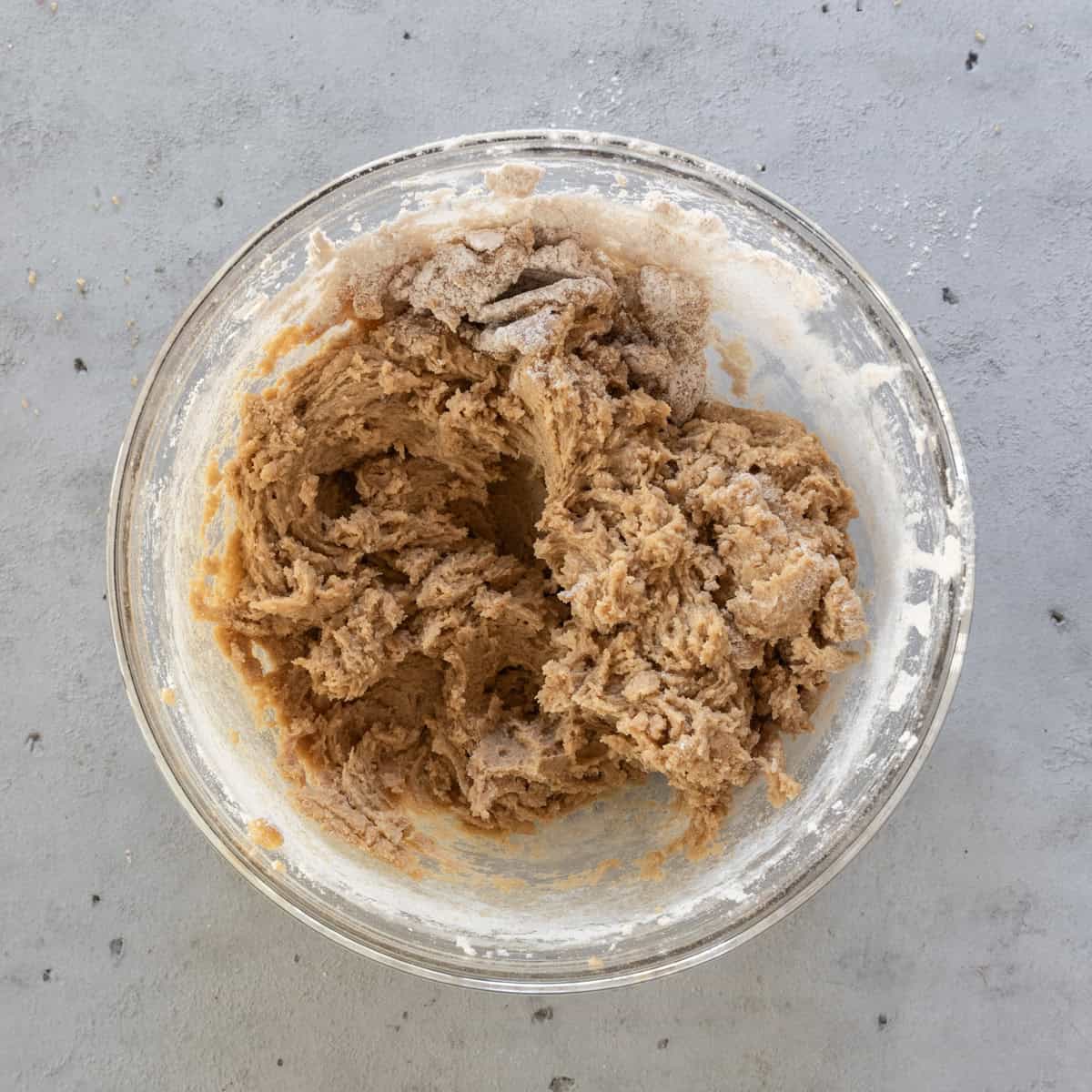 the wet and dry ingredients combined in a glass bowl on a grey background.