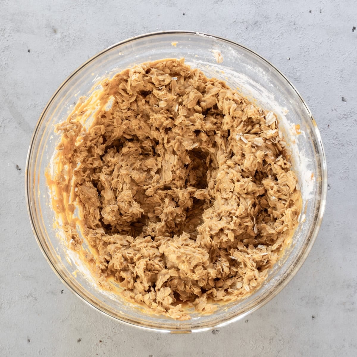 the completed cookie dough in a glass bowl on a grey background.
